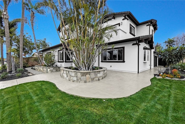 back of house featuring a patio area, fence, a lawn, and stucco siding