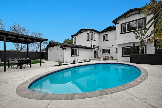 pool with a patio area, fence, and outdoor dining area