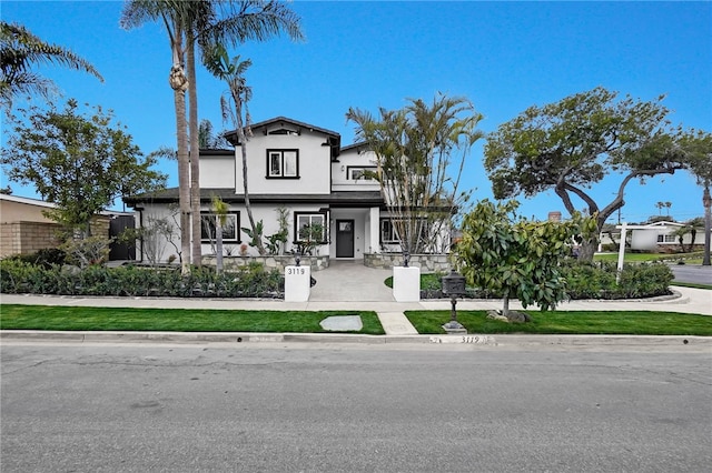 view of front facade with fence and stucco siding