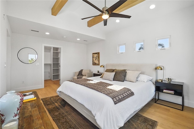 bedroom featuring recessed lighting, wood finished floors, visible vents, beamed ceiling, and a walk in closet