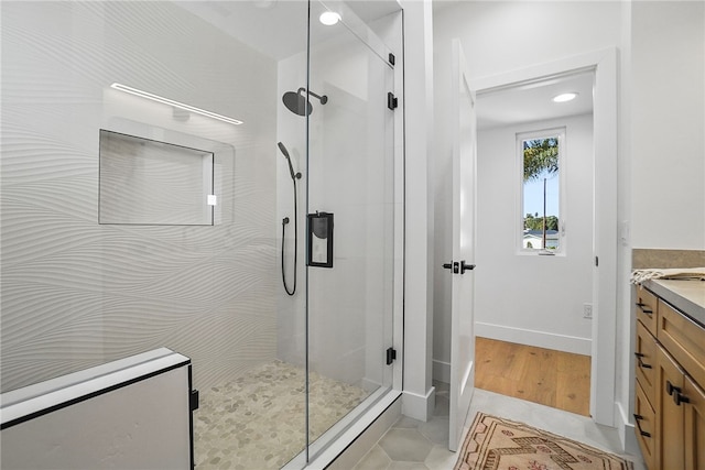 bathroom featuring a shower stall, baseboards, tile patterned flooring, and vanity