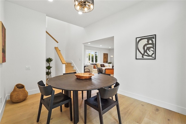 dining room with stairs, baseboards, a chandelier, and light wood-style floors