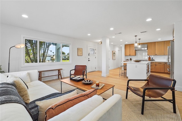 living room with light wood-style floors, baseboards, visible vents, and recessed lighting