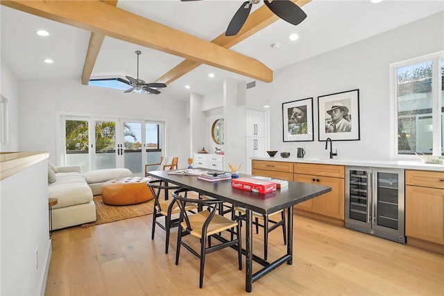 dining room featuring wine cooler, a healthy amount of sunlight, indoor wet bar, and light wood-style flooring