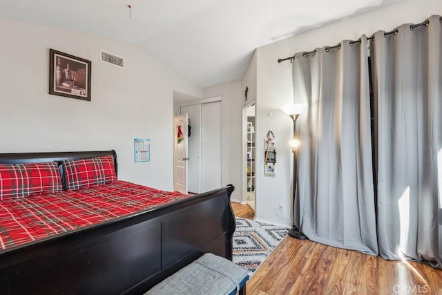 bedroom with wood-type flooring, a closet, and vaulted ceiling