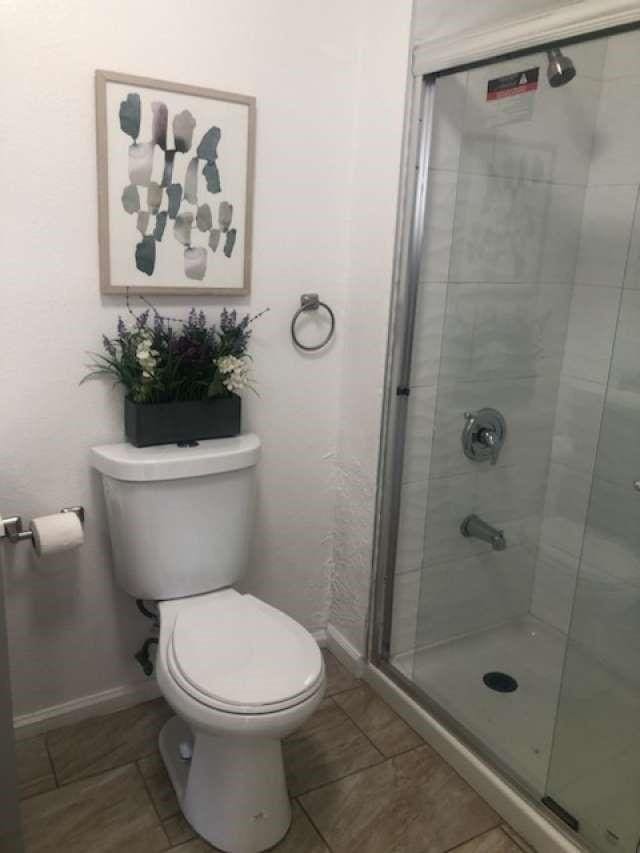 bathroom featuring tile patterned flooring, an enclosed shower, and toilet