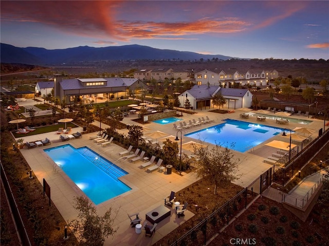 pool at dusk featuring a mountain view and a patio