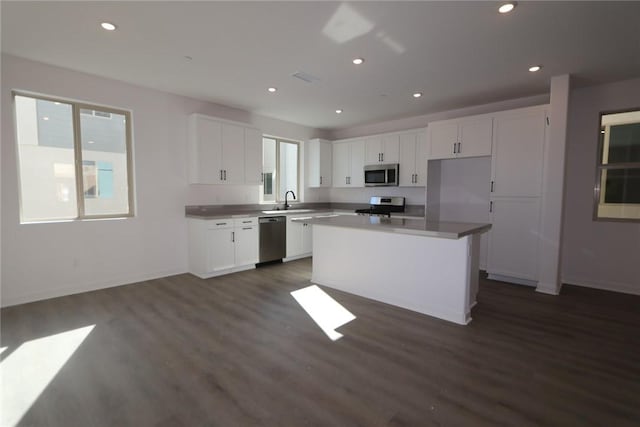 kitchen featuring dark hardwood / wood-style flooring, stainless steel appliances, sink, white cabinets, and a kitchen island