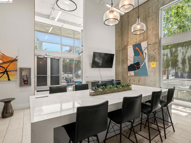 interior space featuring a breakfast bar, a towering ceiling, and pendant lighting