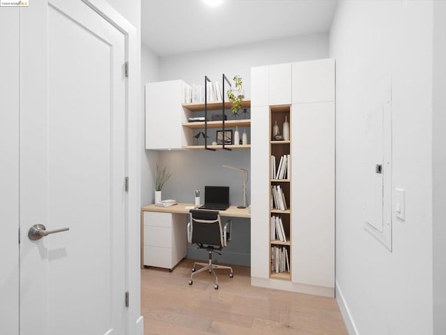 office space with electric panel and light hardwood / wood-style flooring