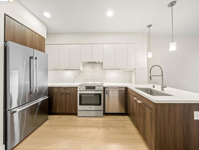 kitchen featuring white cabinets, light wood-type flooring, sink, and appliances with stainless steel finishes