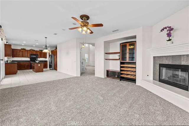 unfurnished living room with light colored carpet and ceiling fan