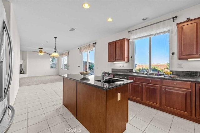 kitchen with light colored carpet, ceiling fan, pendant lighting, fridge, and an island with sink