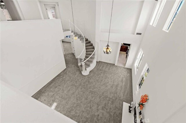 stairway with carpet flooring, a towering ceiling, and a chandelier