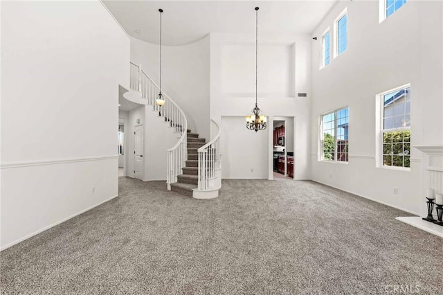 unfurnished living room featuring carpet flooring, a high ceiling, and a chandelier