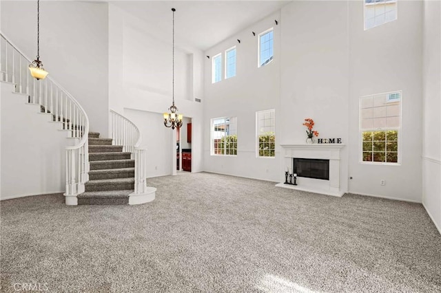 unfurnished living room featuring a towering ceiling, a chandelier, and carpet flooring