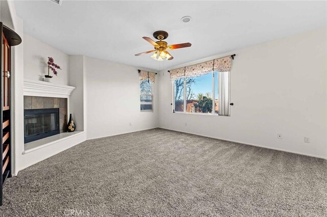 unfurnished living room featuring carpet, ceiling fan, and a tiled fireplace