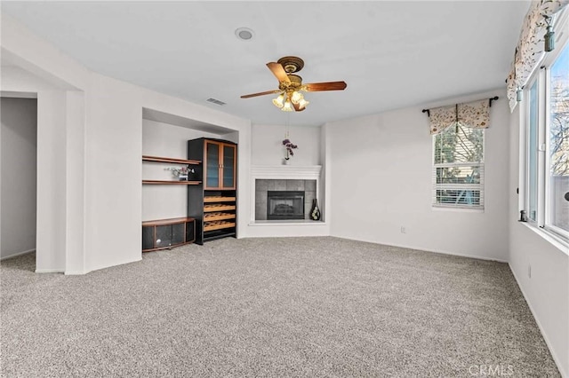 unfurnished living room with carpet flooring, a healthy amount of sunlight, and a tile fireplace