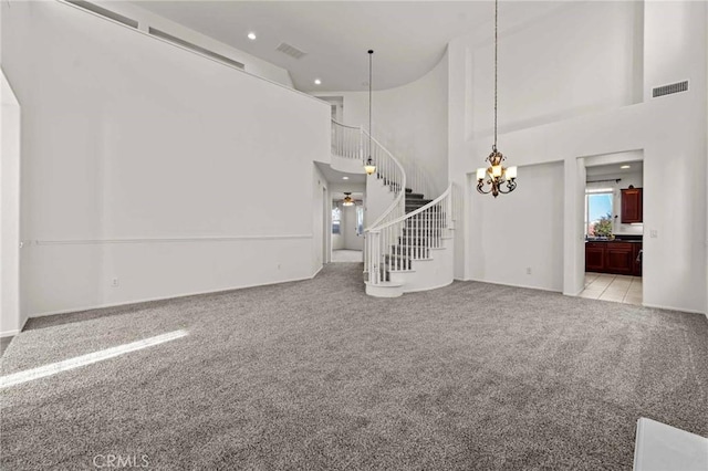 unfurnished living room with light carpet, a towering ceiling, and a notable chandelier