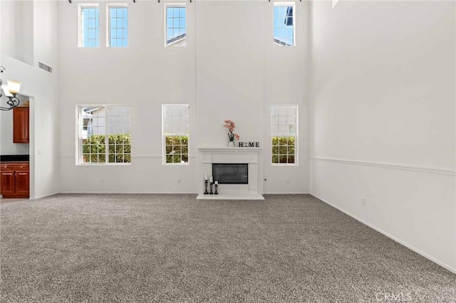 unfurnished living room with carpet, a towering ceiling, and a healthy amount of sunlight