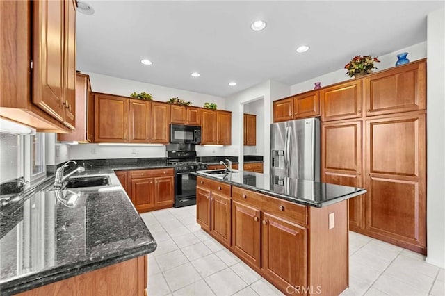 kitchen featuring light tile patterned floors, sink, a center island with sink, and black appliances