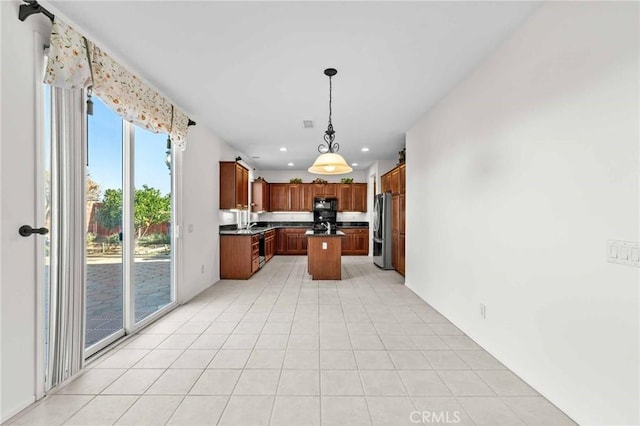 kitchen with light tile patterned flooring, stainless steel fridge, a kitchen island, and pendant lighting