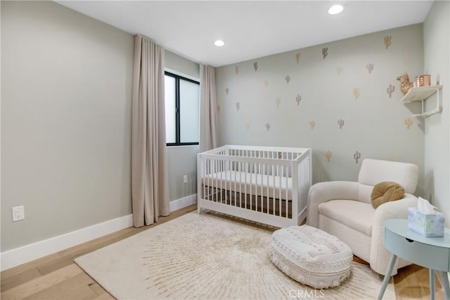 bedroom featuring a nursery area and light hardwood / wood-style floors