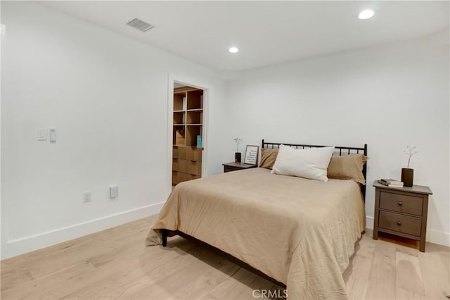 bedroom with a walk in closet and light hardwood / wood-style flooring