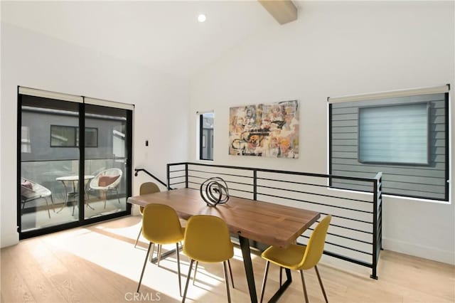 dining room featuring beam ceiling, high vaulted ceiling, and light hardwood / wood-style floors