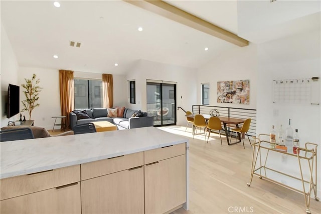 kitchen with vaulted ceiling with beams, light brown cabinets, light stone counters, and light wood-type flooring