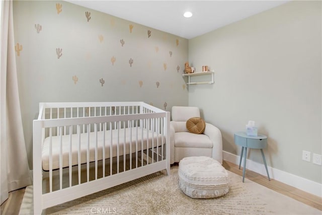 bedroom featuring a crib and light hardwood / wood-style floors