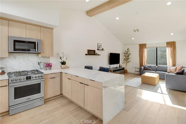 kitchen with beam ceiling, kitchen peninsula, light hardwood / wood-style flooring, and appliances with stainless steel finishes