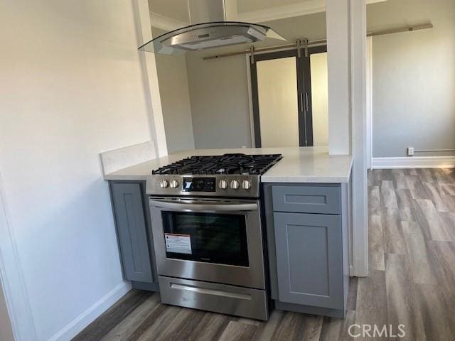 kitchen with hardwood / wood-style floors, gray cabinetry, extractor fan, and stainless steel gas range oven