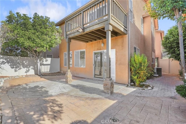 back of house featuring central AC unit, a patio area, and a balcony