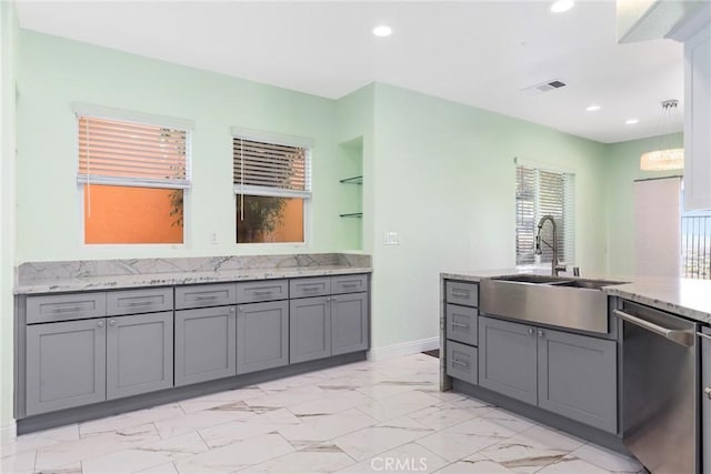 kitchen featuring gray cabinetry, light stone counters, dishwasher, and sink