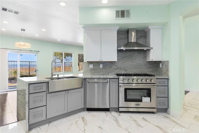 kitchen featuring sink, stainless steel appliances, wall chimney range hood, backsplash, and white cabinets