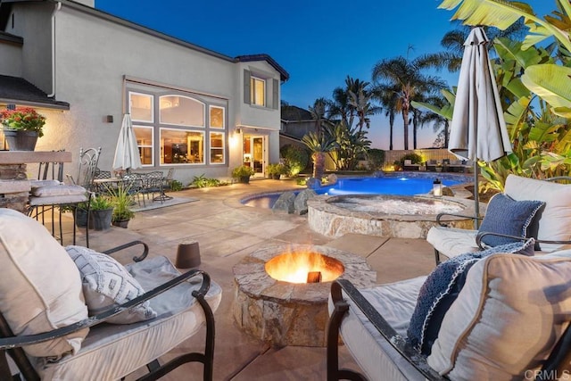 pool at dusk featuring a fire pit and a patio area