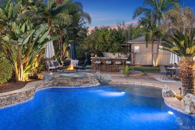 outdoor pool featuring a patio area, fence, a fire pit, and a bar