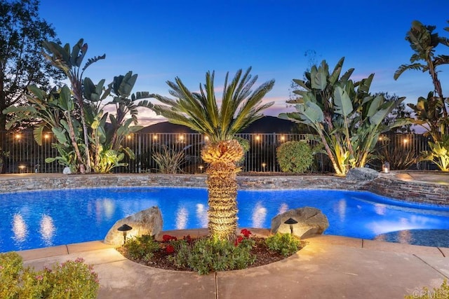 pool at dusk featuring a fenced in pool, a patio area, and a fenced backyard