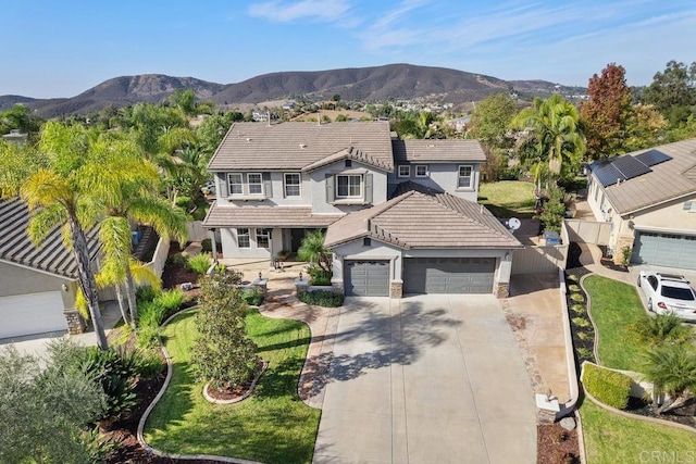 traditional home featuring a mountain view, a garage, a tiled roof, concrete driveway, and stucco siding