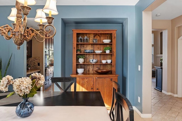 dining room with stone tile flooring, baseboards, and an inviting chandelier