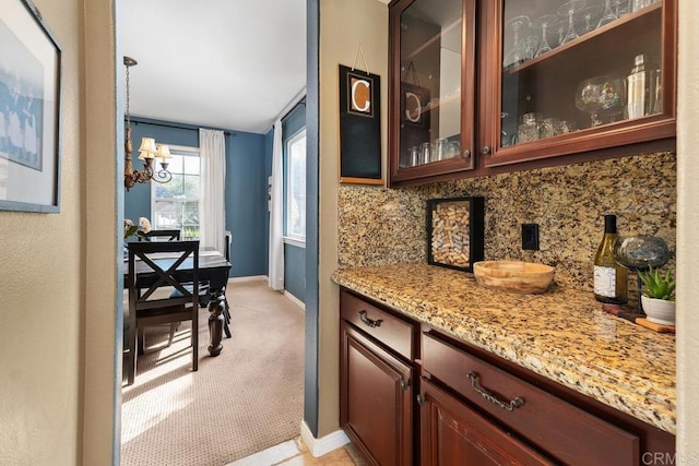 bar featuring a notable chandelier, baseboards, decorative backsplash, and light colored carpet