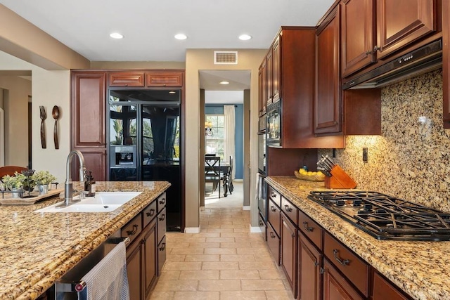 kitchen with under cabinet range hood, a sink, visible vents, black refrigerator with ice dispenser, and stainless steel gas stovetop