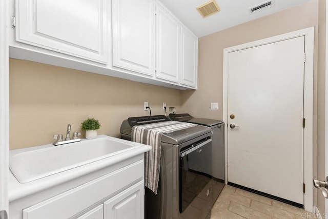 laundry area featuring a sink, cabinet space, washing machine and clothes dryer, and visible vents