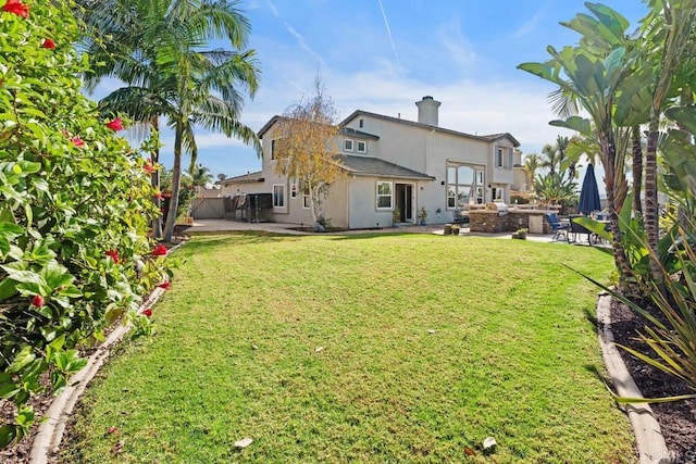 rear view of house featuring a yard, a patio area, fence, and stucco siding