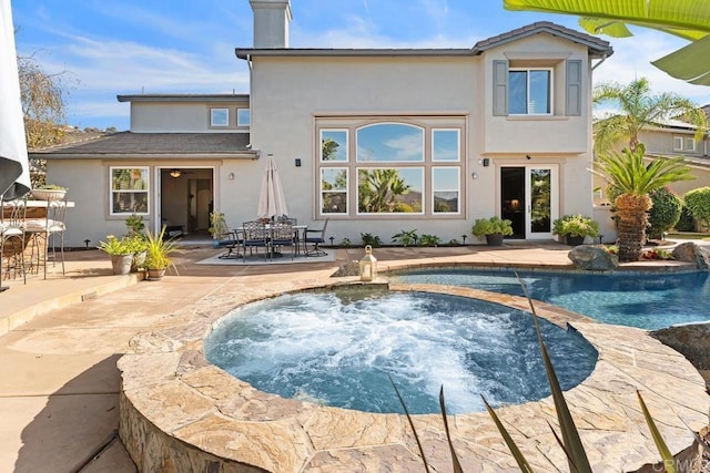 back of house featuring an outdoor pool, a patio, an in ground hot tub, outdoor dining area, and stucco siding