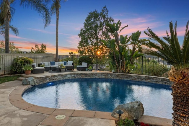 pool at dusk with a fenced in pool, a fenced backyard, a patio, and an outdoor hangout area