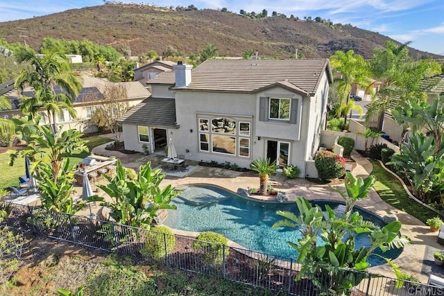 rear view of property with a fenced backyard, a mountain view, a tiled roof, and stucco siding