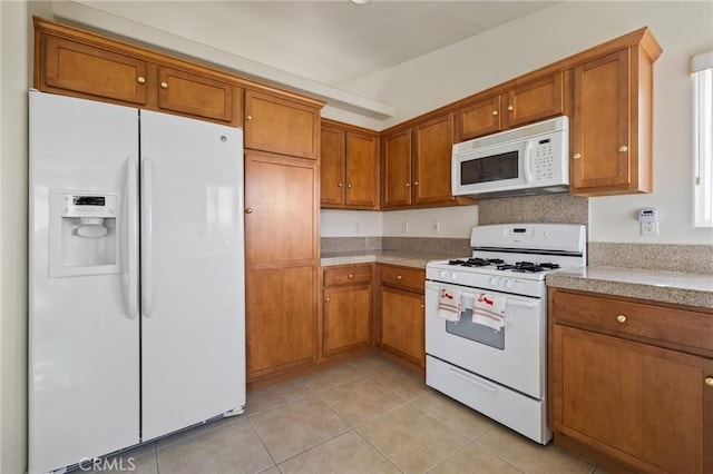 9551 San Rafael Dr, Desert Hot Springs, CA 92240 - kitchen featuring white appliances, brown cabinetry, light countertops, and light tile patterned floors
