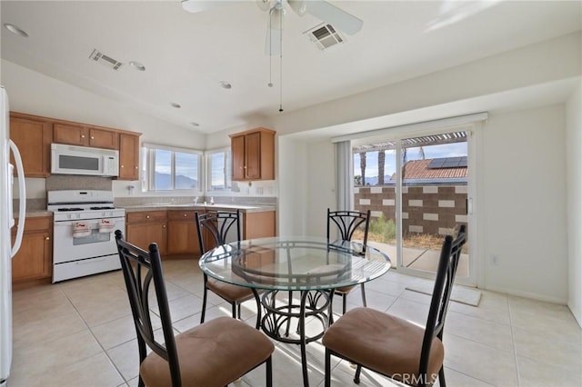 9551 San Rafael Dr, Desert Hot Springs, CA 92240 - kitchen featuring vaulted ceiling, plenty of natural light, light tile patterned floors, and white appliances